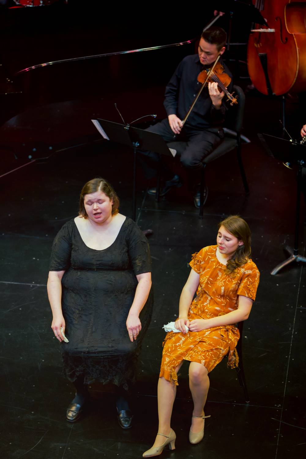 Two women singing and a man playing the violin.